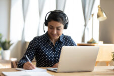 Woman looking at computer with headphones